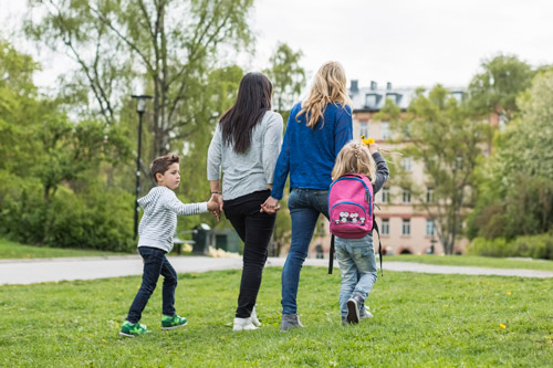 Barn som håller handen med lärare när de går genom en park.